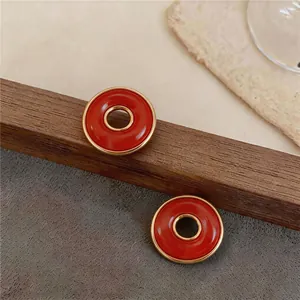 Primer plano de pendientes circulares rojos y dorados vintage en un soporte de madera