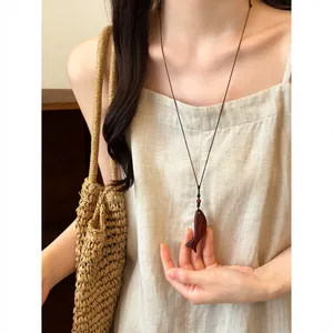 Vue détaillée d'un collier pendentif artisanal en bois sur une robe en lin naturel