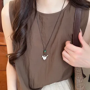 Primer plano del collar con colgante de pájaro en plata cepillada estilo resort