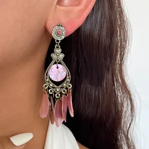 Detailaufnahme von Vintage-Ohrringen mit rosa Muschelquasten und Silbernadel.