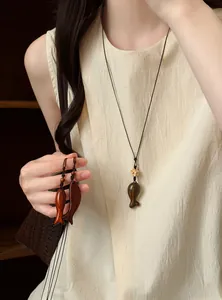 Vue détaillée de pendentifs artisanaux en bois en forme de poisson et tons naturels
