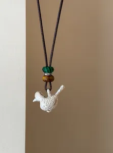 Gros plan détaillé d'un collier pendentif oiseau en argent avec des perles colorées