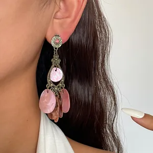 Makroansicht von Vintage-Ohrringen mit rosa Muschelscheiben und Strassdetails