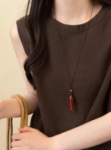 Détail d'un collier vintage avec pendentif poisson en bois sur un haut en lin marron chic.