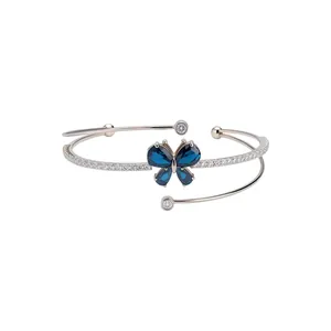 Elegante pulsera rígida multicapa plateada con una mariposa de circón azul brillante