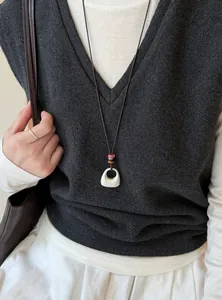 Gros plan d'un collier pendentif argenté brossé minimaliste avec perles sur mannequin.