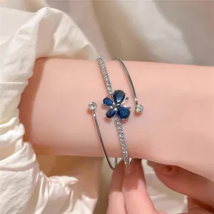 Primer plano de brazalete de mariposa plateado con circonitas azules y blancas en la muñeca