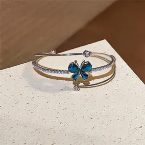 Primer plano de un elegante brazalete abierto multicapa con mariposa de circón azul
