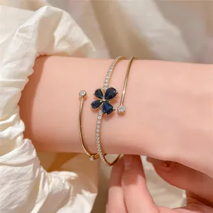 Detalle de un elegante brazalete abierto de varias capas con motivo de flor de circón azul.