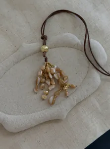 Detailaufnahme einer böhmischen Halskette mit brauner Lederschnur und Muschelquaste