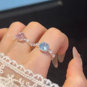 Detailopname van sprankelende roze en blauwe zirkoonringen op hand met witte kant