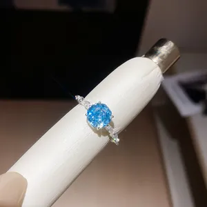 Detailopname van een blauwe zirkonia bloemring met sprankelende lichteffecten op de ringband.