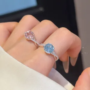 Detailopname van 18k vergulde bloemringen met roze en blauwe zirkoon op vingers.