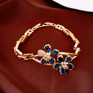Detail showing 18k gold plated bracelet with blue zircon flower design on satin