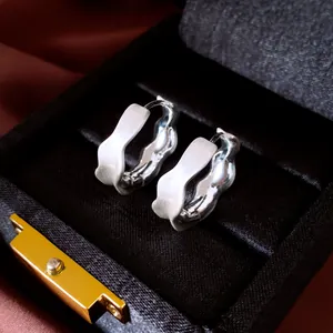 Primer plano detallado de pendientes de aro plateados con textura en su caja de regalo