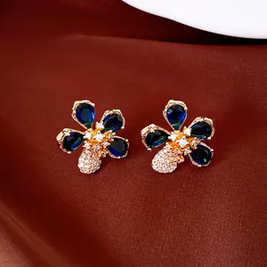 Detailed view of flower-shaped earrings with deep blue teardrop stones and gold plating