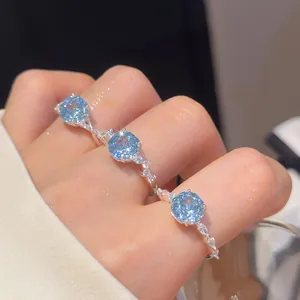 Detailopname van 18k vergulde open ringen met schitterende blauwe ronde zirkonia-stenen