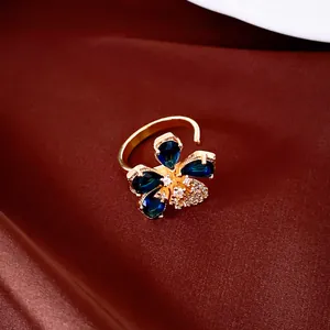 Close-up of an elegant 18k gold plated open ring featuring a blue zircon flower design