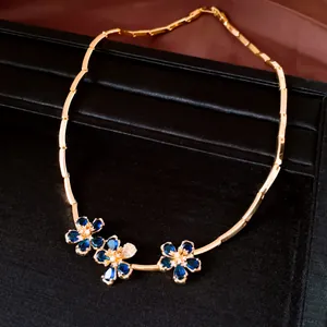 Close-up of 18k gold plated necklace with blue zircon flowers on black display.