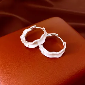 Detalle de pendientes de aro plisados en plata con acabado cepillado y un borde ondulado
