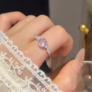 Close-up van een roze ronde zirkoon ring aan een vinger met wit kant