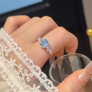 Close-up van een elegante zilveren bloemring met ronde lichtblauwe zirkoon op de hand