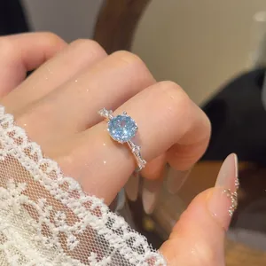 Detailopname van een lichtblauwe kussengeslepen zirkoon ring aan de hand met kant