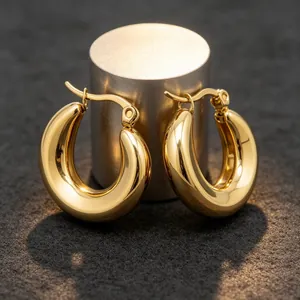 Detalle de pendientes gruesos en forma de U de acero inoxidable dorado pulido en soporte.