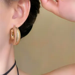 Detaillierte Nahaufnahme von goldenen Creolen mit eleganter horizontaler Rillenstruktur.