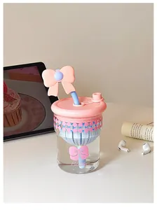 Nahaufnahme einer süßen Glaswasserflasche mit dekorativer rosa Schleife und Strohhalm