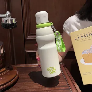 Detail shot of cream stainless steel water bottle with green strap in lifestyle setting