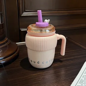 Gros plan d'une tasse à café nuage rose avec paille violette sur un bureau en bois.