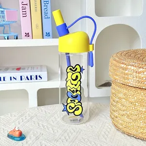 Detail of a trendy high-borosilicate glass water bottle with yellow lid and blue straw.