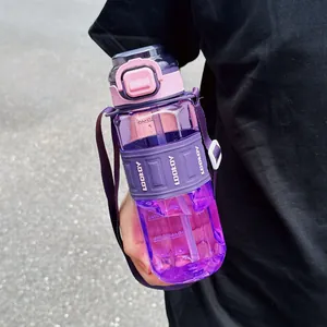 Grande gourde de sport violette avec paille et bandoulière tenue à la main dehors.