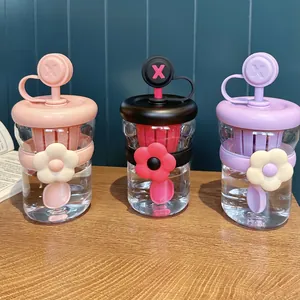 Dettaglio di tre tazze in plastica colorata con fiori, cannucce e infusori per il tè
