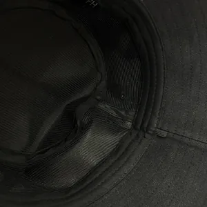 Close-up of the breathable interior lining and stitching of the black cotton bucket hat.