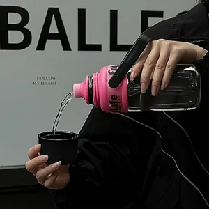 Große tragbare Kunststoff-Wasserflasche mit Griff beim Einschenken von Wasser in Becher