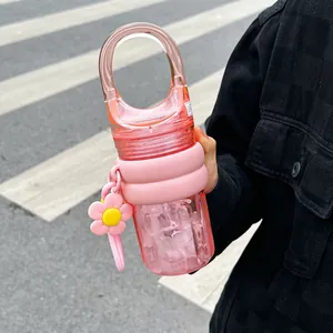 Close-up view of a stylish pink portable water bottle with flower charm and handle