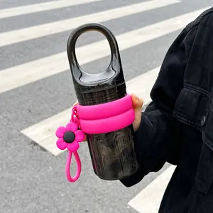 Close-up of a black portable water bottle with pink silicone sleeve and flower charm