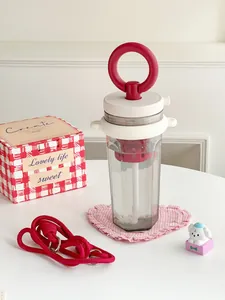 Portable square water bottle with red infuser and ring handle in lifestyle setting.