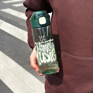 Primer plano de una botella de agua deportiva verde con estampado Street Music al aire libre