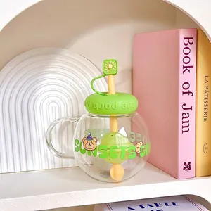 Close-up of a cute spherical glass tea cup with straw and filter in a cozy shelf setting
