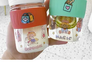 Close-up of cute glass coffee cups with colorful silicone sleeves and cartoon prints