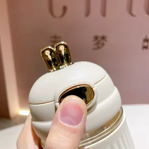 Vue détaillée du couvercle de tasse lapin blanc avec oreilles dorées et bouton poussoir