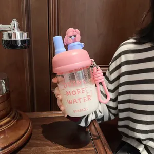 Detail of cartoon glass water bottle with pink lid and cute figurine accessory