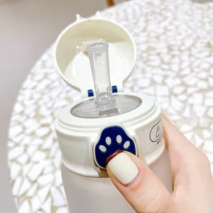 Close-up of cute water bottle lid featuring a blue cat paw button and pop-up straw.