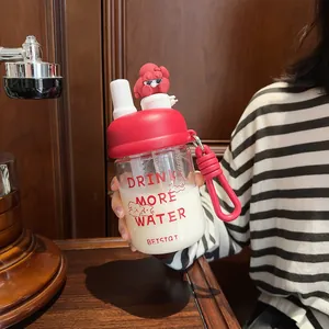 Detail view of a cute red glass water bottle with a cartoon character and carry strap