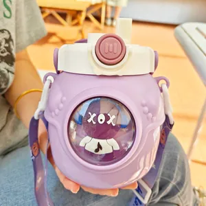 Gros plan d'une bouteille isotherme violette avec une poupée mignonne et une sangle.