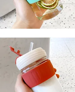 Detail of minimalist glass coffee cup with straw and colorful silicone sleeve