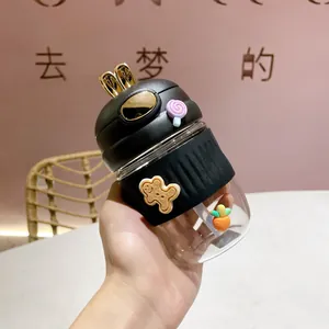 Gros plan d'une jolie gourde en verre lapin avec housse en silicone et breloques